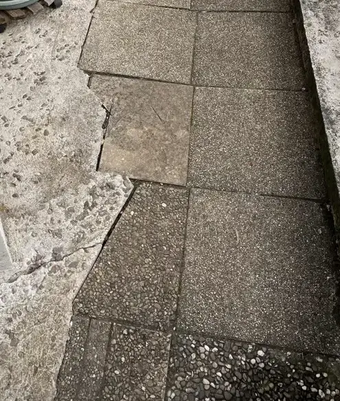 Dallage extérieur fracturé et décroché le long d'un mur
