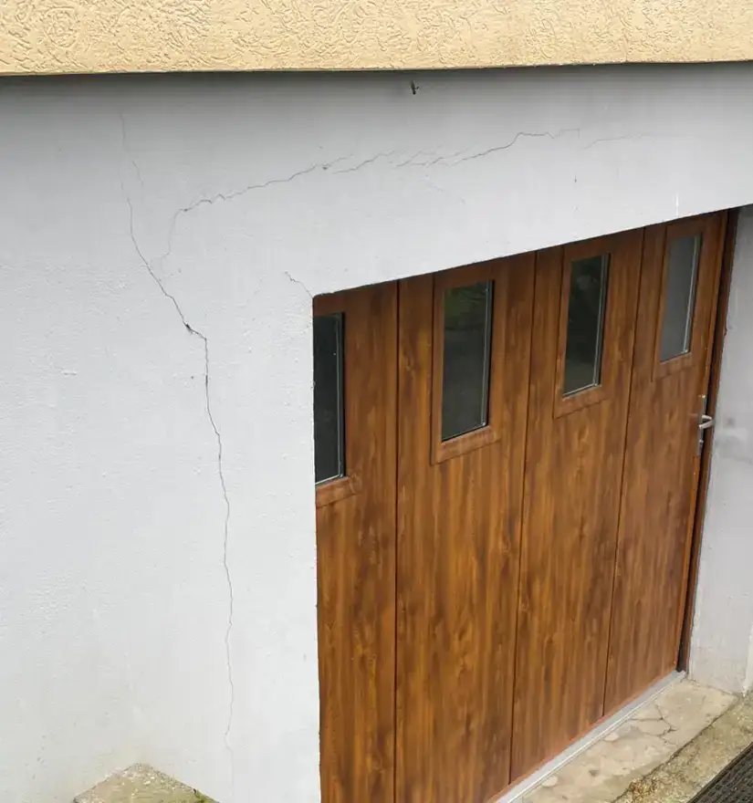 Fissure marquée partant de l'angle d'une baie sur une façade enduite