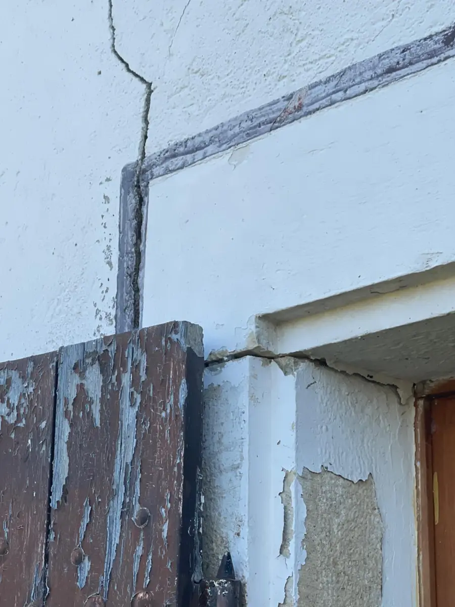 Fissure de façade partant de l'angle d'un encadrement de porte