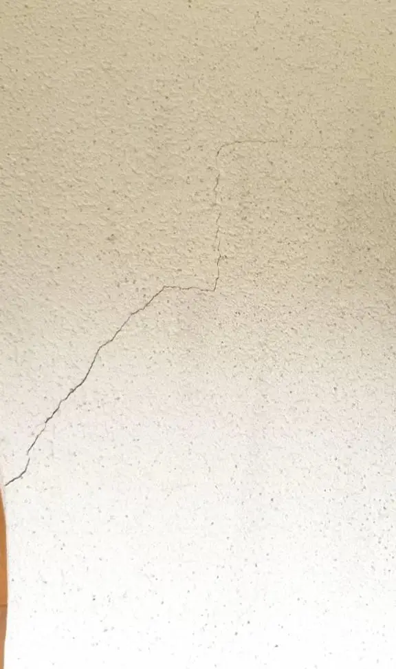 Fissure fine sur un mur intérieur enduit, type de fente concernée par le calicotage
