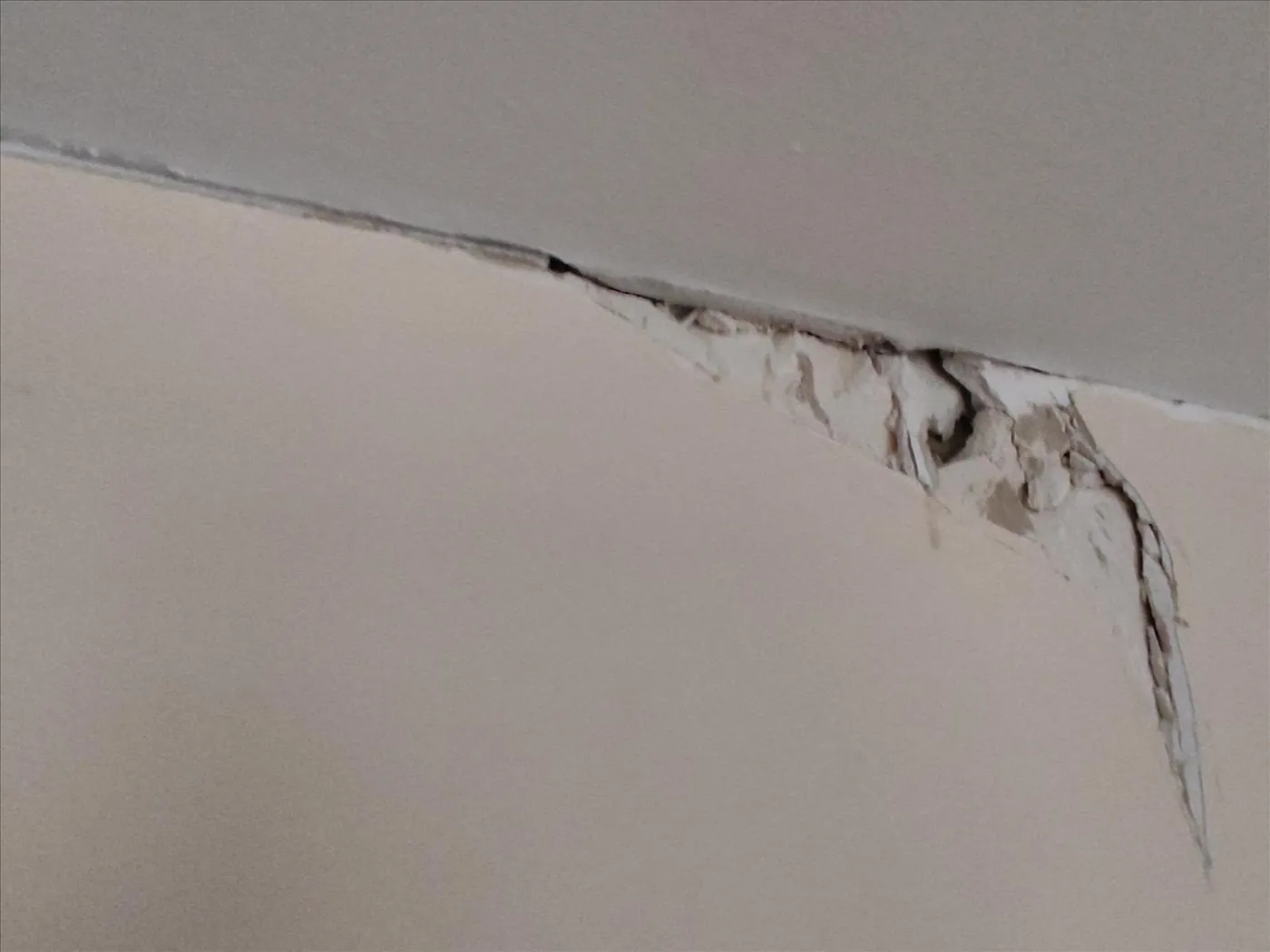 Fissure et dégradation du plâtre à la jonction mur-plafond