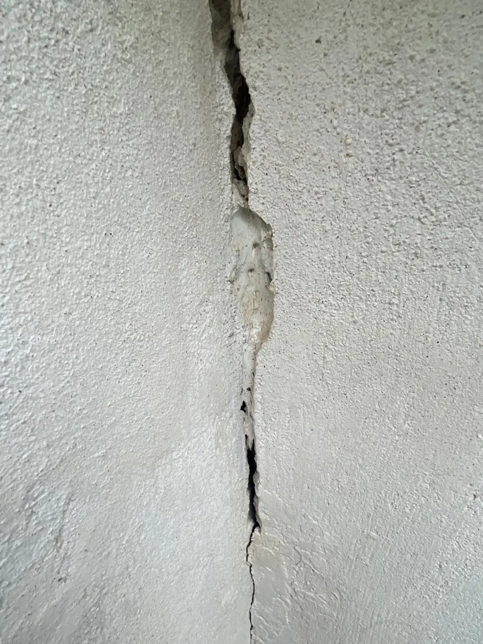 Fissure verticale profonde dans un enduit de façade, objet type d'une contre-expertise