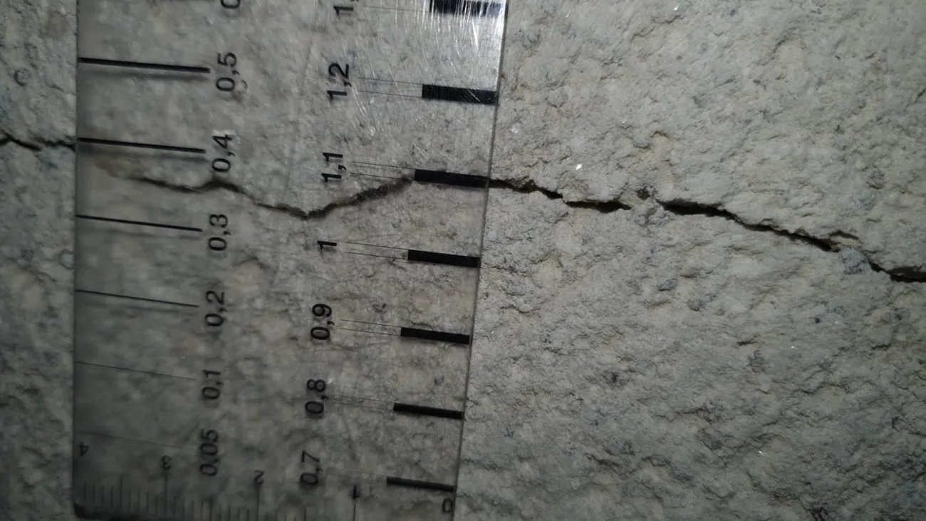 Règle graduée posée contre une fissure de mur pour en mesurer la largeur