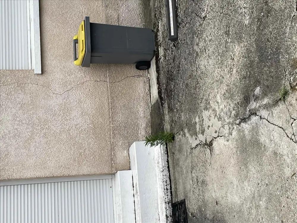 Mur de façade fissuré à côté d'un volet roulant