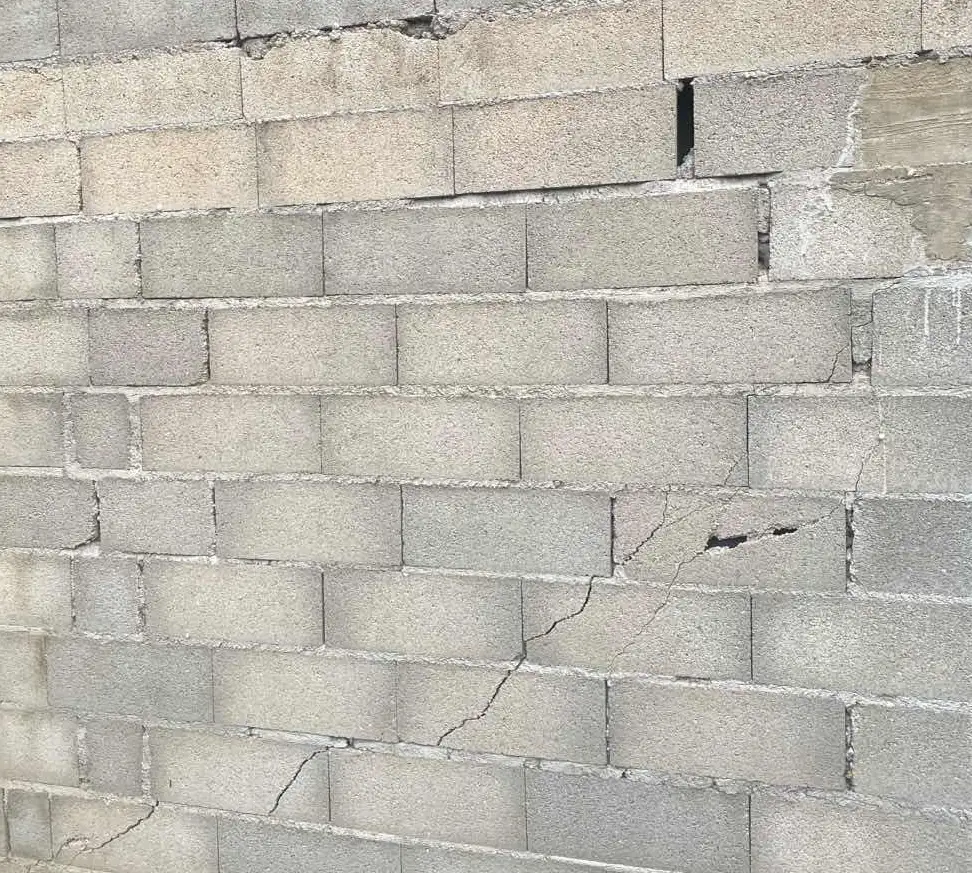 Fissure en escalier dans un mur en parpaing partant de l'angle d'une ouverture