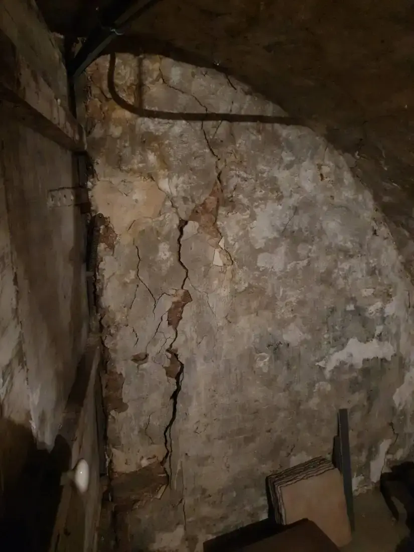 Mur de sous-sol d'immeuble ancien parcouru de fissures