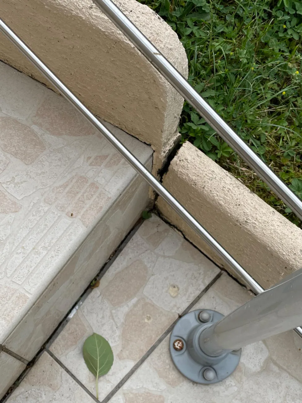 Terrasse au dallage fissuré le long d'un poteau, désordre typique traité par injection