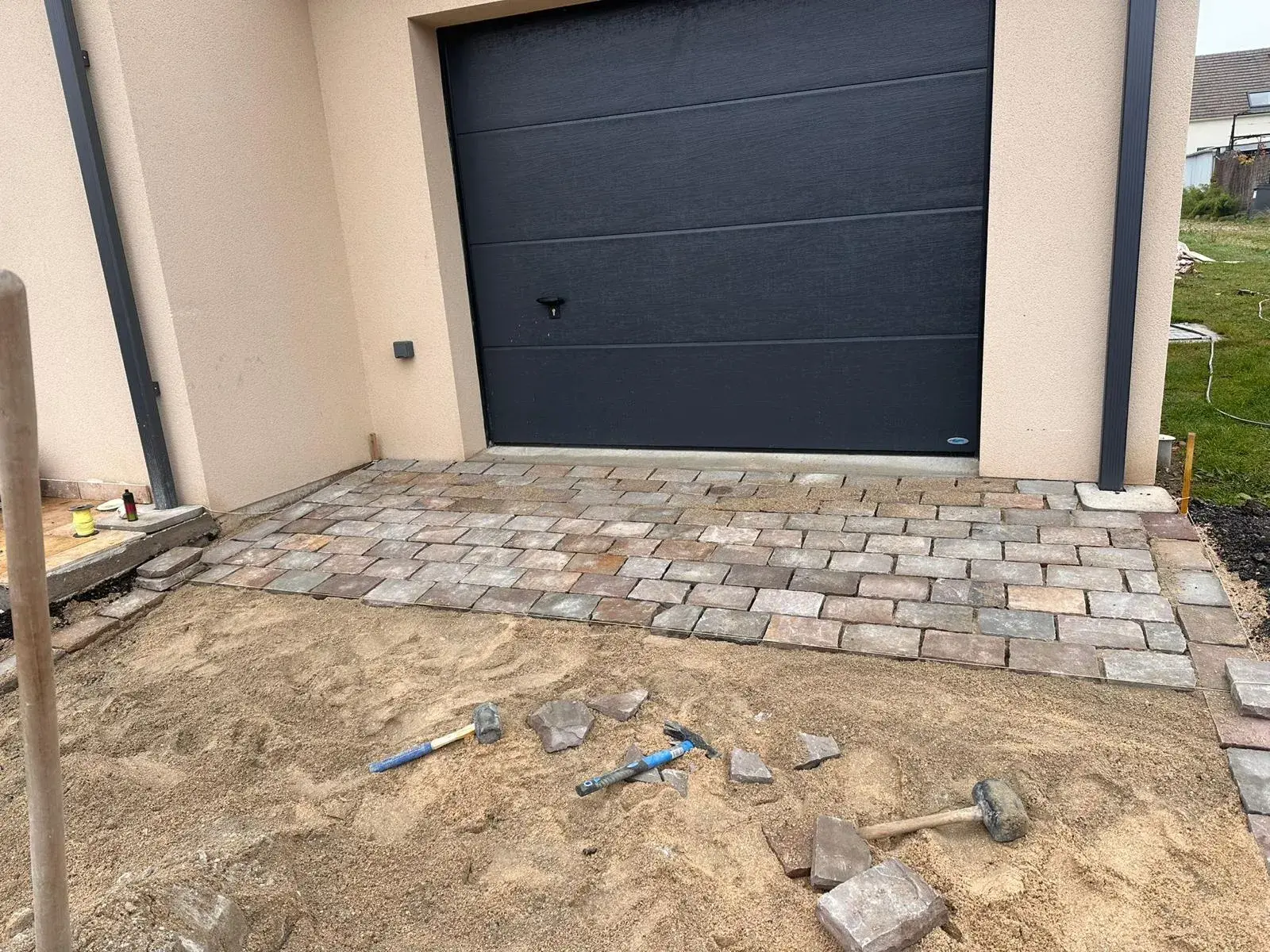 Porte de garage et abords pavés d'une maison livrée, équipements couverts par les garanties
